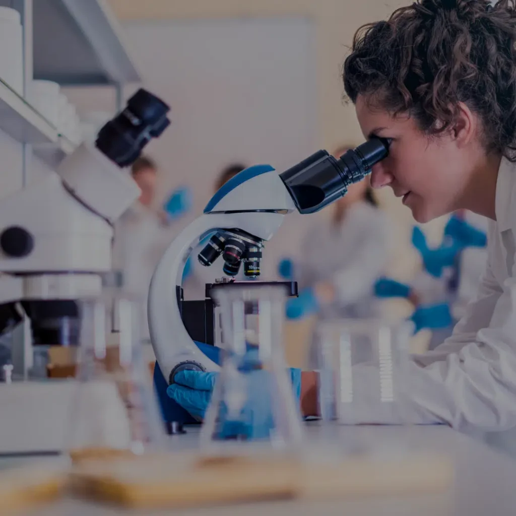 Woman looking through a microscope in a lab